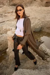 Tapado de silueta recta con estampado de cuadros, escote en V profundo y cierre frontal con un único botón. Presenta mangas largas con leve volumen, tajos laterales y terminaciones con flecos en el ruedo.