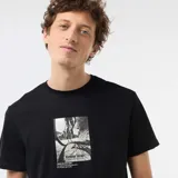 Remera negra de manga corta con cuello redondo y diseño gráfico estampado en el centro del pecho.