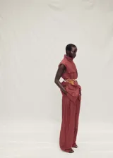 Chaleco largo de estilo utilitario color rojizo, con cuello solapa, sin mangas y cierre frontal con botones. Presenta cuatro bolsillos de parche con solapa en la parte delantera y un acabado con efecto arrugado.