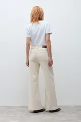 Jean de corte wide leg en color beige claro, con tiro medio y cierre frontal con botón y cremallera. Presenta un diseño de cinco bolsillos y costuras reforzadas.