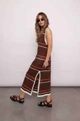 Vestido largo tejido de punto color marrón con rayas horizontales blancas y naranjas, cuello redondo y tajos laterales.