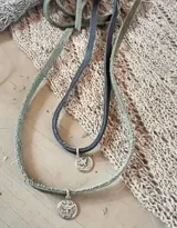 Gargantilla con dije redondo de plata 925 con la imagen del Espíritu Santo, colgando de una tira de cuero azul.