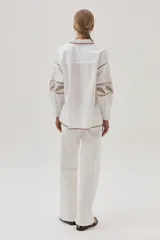 Camisa blanca de mangas largas abullonadas con bordados combinados y guardas, además de delicados bordados en el cuello y el bajo.