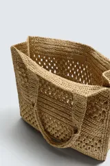 Bolso tipo shopper de diseño trenzado en color tostado, con estructura rectangular, dos asas de mano y compartimento principal abierto.