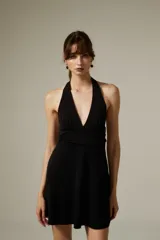 Vestido corto negro con escote halter profundo y corte ajustado al cuerpo.