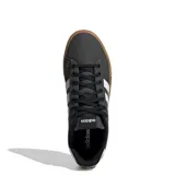 Championes urbanos Adidas Daily 4.0, color negro con las tres tiras laterales en blanco y suela de goma color caramelo. Presentan capellada de tela con cordones negros y diseño de plataforma baja.