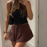 Short pollera marrón con diseño de capas y short integrado por debajo. Cuenta con cintura elástica y cordón ajustable.