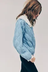 Campera acolchada ligera de denim en mezcla de algodón y lyocell, modelo Divided de H&M. Presenta cuello redondo, cierre frontal con botones a presión, hombros ligeramente caídos, mangas abullonadas y elástico revestido en los puños y el dobladillo inferior. Diseño pespunteado con ondas.