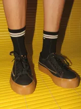 Championes de lona negra con plataforma y puntera de goma marrón, cordones negros y costuras en contraste.