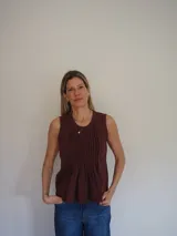 Blusa sin mangas de algodón color blanco, con delicadas tablas en el frente y terminaciones levemente desflecadas, de corte suelto y liviano.