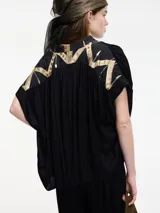 Blusa color crema de manga corta con bordados en la parte trasera.