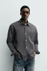 Camisa de corte relajado confeccionada en una mezcla de lyocell y algodón con efecto lavado. Presenta cuello solapa, manga larga con puños abotonados, bolsillo de plastrón en el pecho y cierre frontal con botones.
