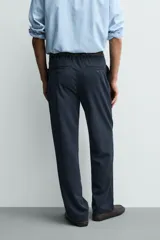 Pantalón de corte recto confeccionado en tejido elástico, con cintura elástica, pliegues frontales, bolsillos laterales y bolsillos traseros de vivo con botón.