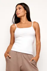Musculosa de viscosa acanalada con elastano, color blanco, con escote recto y breteles finos regulables. Diseño ajustado al cuerpo.
