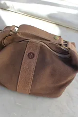 Neceser de cuero color marrón, con diseño estructurado, cierre superior y manija superior fija.