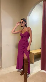 Vestido midi color uva con escote corazón, tirantes finos y aberturas laterales en la cintura. Presenta un diseño con frunces frontales y una falda con tajo lateral.