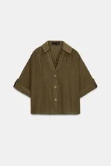 Camisa de cuello solapa y escote pico, color verde militar, con manga corta con trabilla y botón, y cierre frontal con botones.