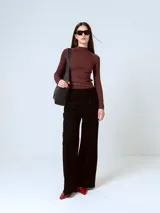Pantalón de corte sastrero y pierna ancha, color negro, con cintura alta y pinzas frontales.