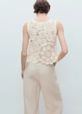 Top de crochet color crudo, sin mangas, con cuello redondo y diseño floral translúcido.