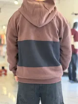 Hoodie de felpa con capucha y medio cierre frontal, diseño en bloques de color celeste y blanco, con bordados decorativos en el pecho.