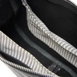 Bandolera de cuero con textura granulada, diseño compacto con cierre superior y correa ajustable al hombro. Presenta el logo de la marca grabado en la parte frontal.