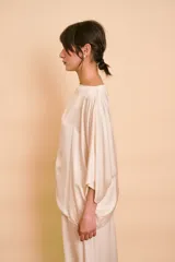 Blusa de satén color beige, con escote bote, corte holgado y mangas amplias tipo kimono.