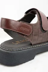 Sandalias marrones de cuero con suela de goma negra y ajuste con velcro.