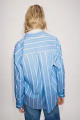 Camisa ZW Collection de algodón, con diseño a rayas verticales celestes y blancas, cuello solapa, manga larga y bolsillo de parche en el pecho con cierre frontal de botones ocultos.
