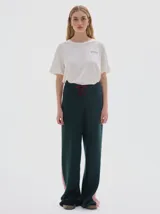 Pantalón tejido de corte recto y holgado, color negro con franja lateral en contraste y tajo en el ruedo. Cuenta con cintura elástica con cordón ajustable.