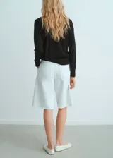 Jersey de punto fino color negro, con cuello en pico y detalle de fular integrado en el escote. Presenta un diseño recto y mangas largas.