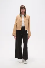 Campera corta color beige, con cuello camisero estampado floral en tonos oscuros y cierre frontal de botones a presión. Presenta bolsillos superiores con solapa y pespuntes verticales en el frente.