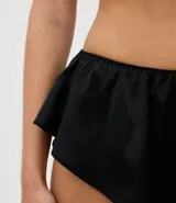 Short de pijama marca Lov, confeccionado en satén negro, con cintura elástica y detalle de volados en el ruedo.