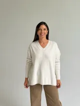 Sweater de punto color beige con escote en V, diseño holgado y costura central vertical. Presenta mangas largas con puños acanalados y ruedo con terminación acanalada.