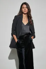 Blazer negro de corte recto con solapa clásica y mangas tres cuartos con detalles de trabilla y botón metálico.