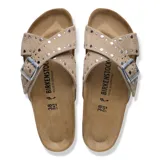 Sandalias Birkenstock modelo Siena Rivet LEVE, de color taupe, con tiras cruzadas de gamuza decoradas con tachas metálicas, hebilla ajustable y plantilla anatómica de corcho.