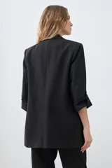 Blazer de corte recto y diseño minimalista, color blanco, con solapas clásicas, bolsillos frontales con solapa y mangas tres cuartos con detalle de botones.