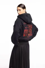 Campera negra de algodón con cierre frontal, capucha, bolsillos laterales y detalles de tachas metálicas en la capucha y los bolsillos. Presenta un estampado frontal con texto en tono rojizo.