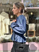 Blusa de manga larga con cuerpo fruncido mediante elásticos y terminación con volados en el ruedo. Presenta un diseño versátil y adaptable.