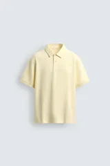 Polo de hombre color amarillo pálido, de corte regular fit, confeccionado en tejido piqué. Presenta cuello solapa con cierre frontal de botonadura y manga corta con acabados en rib.