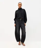 Pantalón baggy balloon de jean negro, tiro medio, con calce amplio, recortes estructurales y botamanga ajustada. Incluye bolsillos delanteros y traseros, y un cinturón de PU negro con hebilla metálica circular.