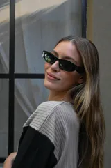 Lentes de sol con armazón rectangular de estilo moderno y minimalista, en color negro con cristales oscuros.