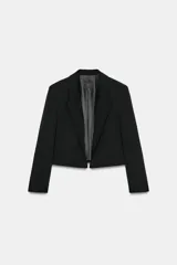 Blazer corto de corte recto con cuello de solapa, manga larga y hombreras. Presenta un diseño minimalista sin botones y forro interior a tono.