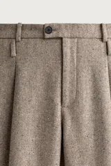 Pantalón relaxed fit de hombre color marrón con textura estructurada, cintura con pliegues frontales, bolsillos laterales y cierre frontal con cremallera y botón.