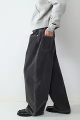 Jean de corte balloon para hombre, confeccionado en denim negro con costuras en contraste. Presenta un diseño de cinco bolsillos, cierre de botón y cremallera, con una silueta amplia y relajada.