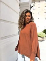 Sweater de punto color moka, con diseño oversize, cuello redondo, costura central vertical y puños acanalados.