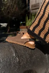 Zuecos de cuero marrón con talón descubierto y suela de goma.