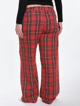 Pantalón de dormir de franela de algodón con estampado de cuadros escoceses en tonos rojos, negros y blancos. Presenta un corte recto y holgado, cintura elástica con cordón ajustable y bolsillos laterales.