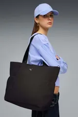 Bolso tipo shopper Puma Up de color negro, con asas de hombro y el logo de la marca en dorado en la parte frontal.