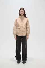 Campera acolchada de poliamida en color beige, con diseño de costuras en rombos, cuello alto, cierre frontal y bolsillos delanteros con solapa.