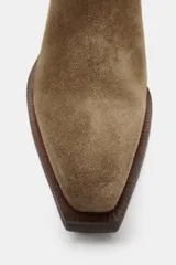 Botín estilo cowboy confeccionado en serraje, con detalle de pespuntes en el cuerpo, cierre lateral mediante cremallera y acabado en punta con tacón cuadrado.